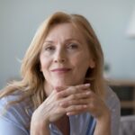 Head shot close up portrait attractive middle-aged woman resting on cozy sofa alone at home staring at camera, posing for photo looks peaceful and confident. Midlife, medical insurance cover for older